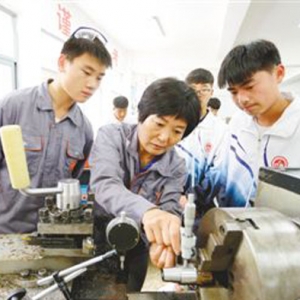 江蘇東海中等專業學校的老師在車床旁向學生講解工件如何打表